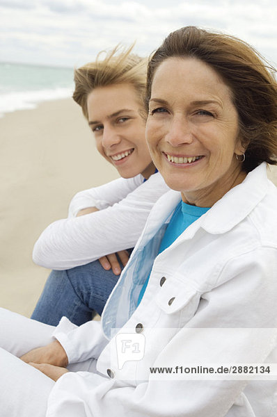 Teenager-Junge sitzt mit seiner Großmutter am Strand