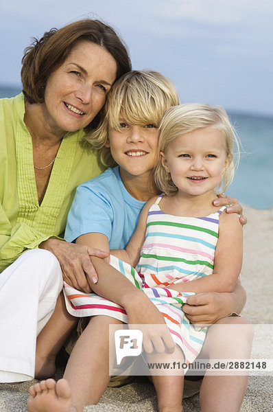 Woman sitting with her grandchildren on the beach