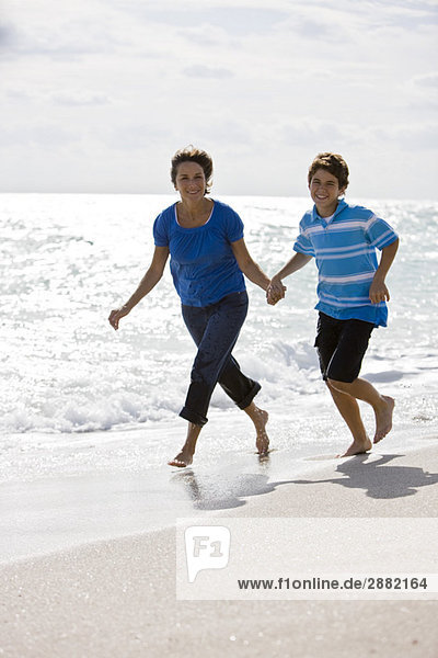 Woman running on the beach with her grandson