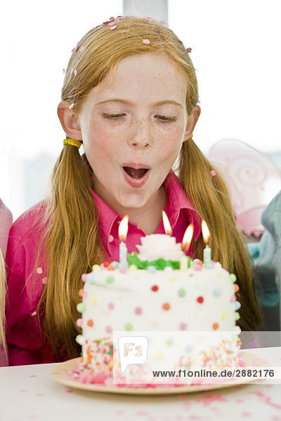 Mädchen beim Ausblasen von Kerzen auf einem Geburtstagskuchen
