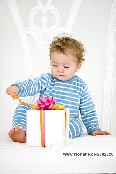 Kleiner Junge spielt mit einem Geschenk im Sessel