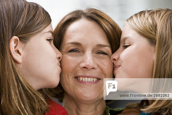 Nahaufnahme von zwei Mädchen  die ihre Großmutter küssen