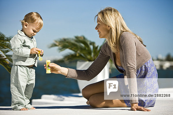 Frau hält eine Seifenblasenflasche vor ihren Sohn