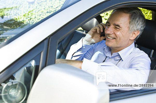 Mann sitzt im Auto und redet auf dem Handy