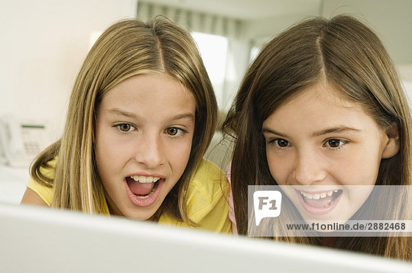 Zwei Mädchen schauen auf einen Laptop mit Überraschung