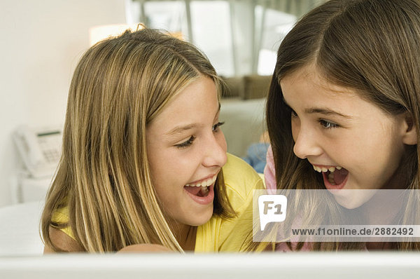 Close-up of two girls smiling at each other with a surprise