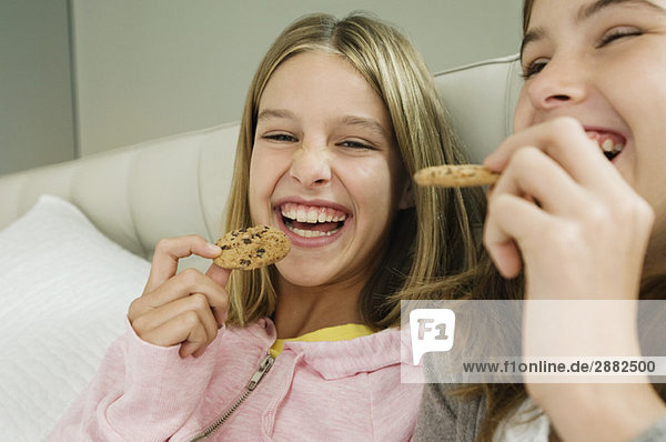 Two girls eating chocolate cookies