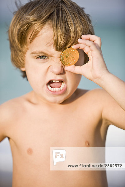 Porträt eines Jungen mit einer Münze vor dem Auge