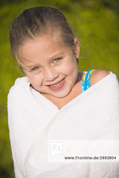 Porträt eines Mädchens in ein Handtuch gewickelt und lächelnd