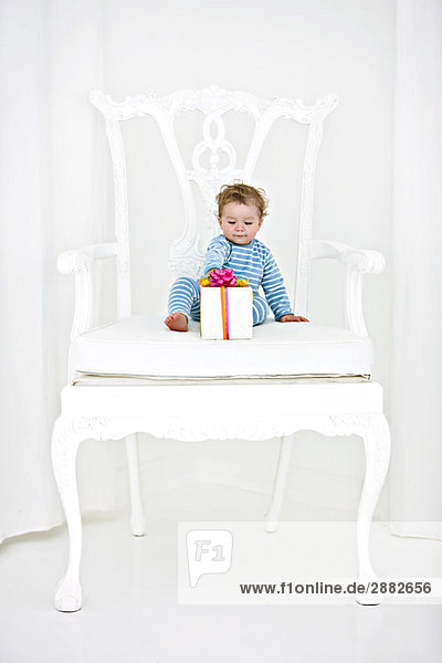 Junge im Sessel sitzend mit einem Geschenk