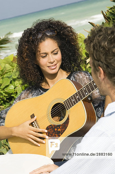 Frau spielt Gitarre vor einem Mann