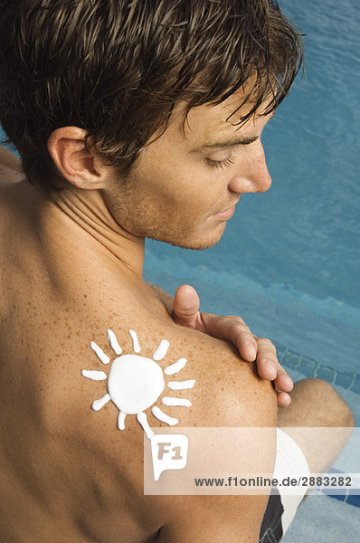 Mann mit Sonnenform auf der Schulter am Beckenrand