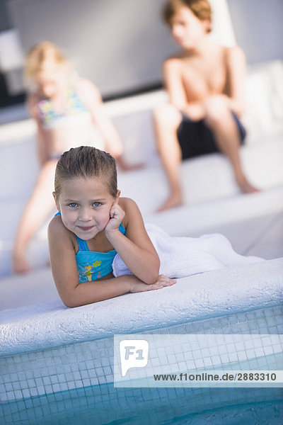 Porträt eines Mädchens am Pool liegend und lächelnd