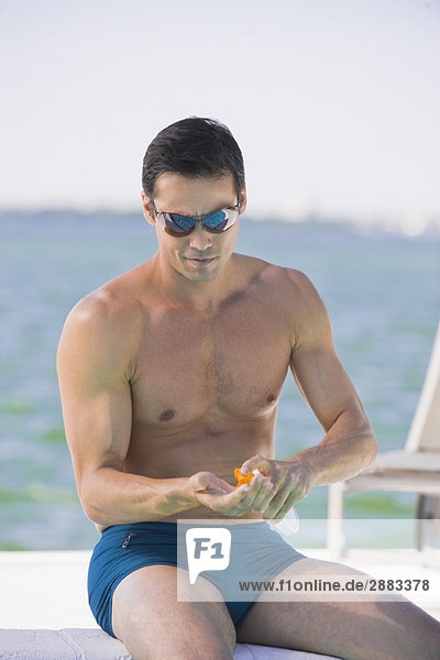 Man applying suntan lotion at the poolside