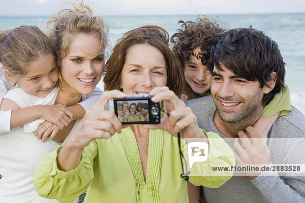 Frau beim Fotografieren ihrer Familie mit einer Digitalkamera
