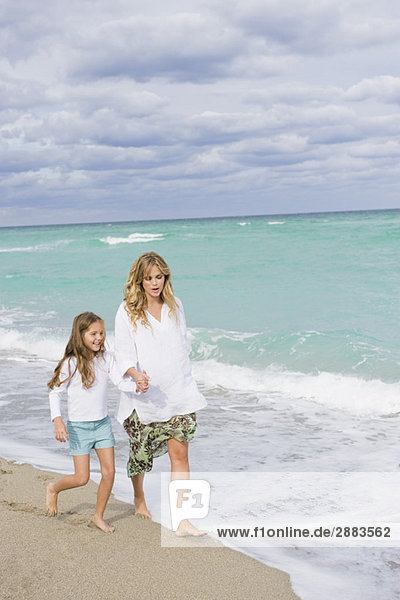 Woman walking on the beach with her daughter