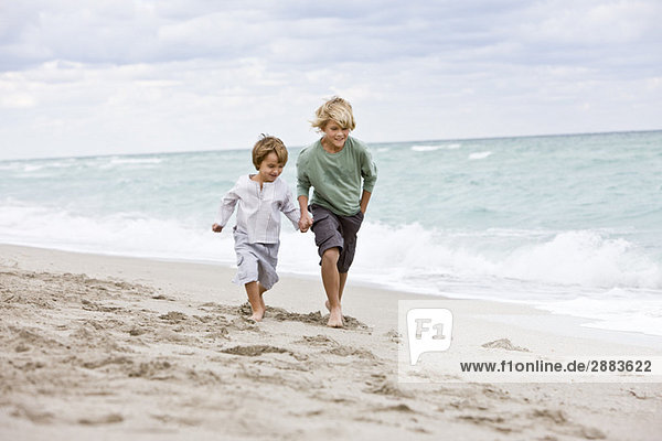 Zwei Jungen  die am Strand rennen.