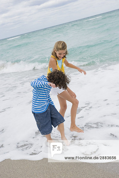 Junge spielt mit einem Mädchen am Strand