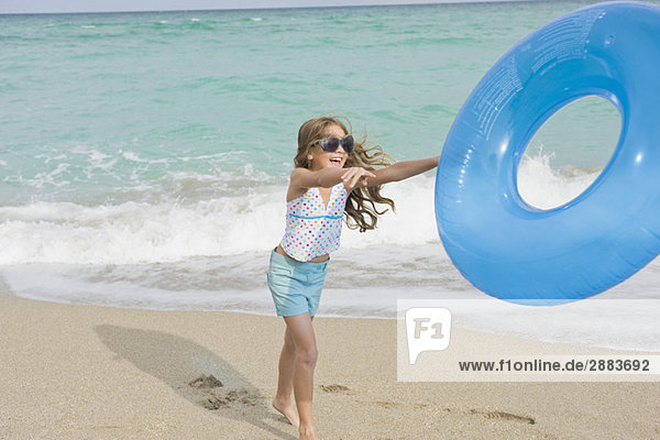 Girl playing with an inflatable ring on the beach