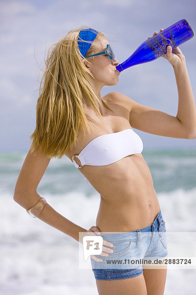 Frau trinkt Wasser am Strand