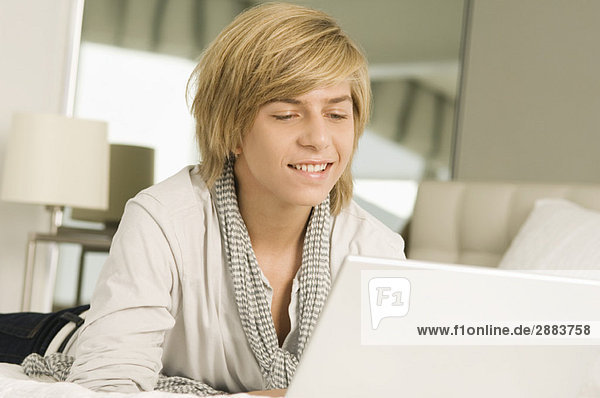 Teenage boy working on a laptop and smiling