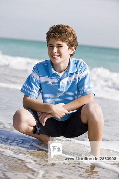 Boy crouching on the beach