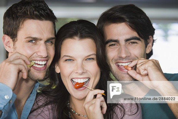 Portrait of three friends eating fruits