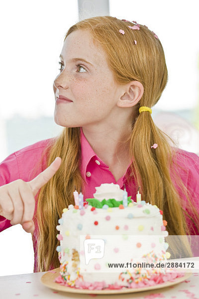 Girl pointing at a birthday cake