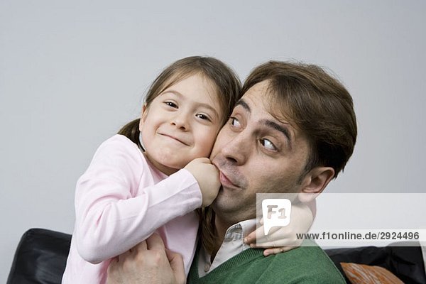 A young girl pretend punching her father in the mouth