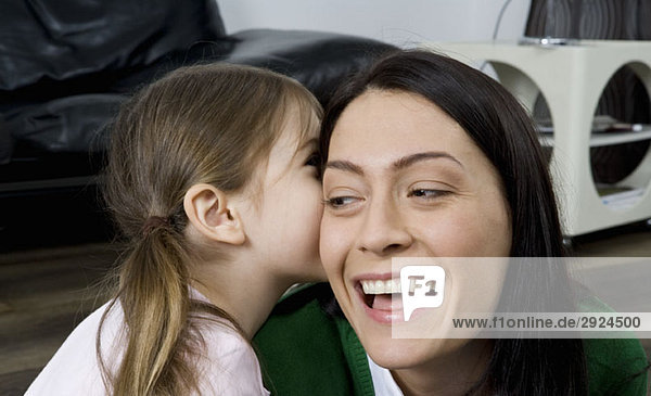 Eine Tochter flüstert ihrer Mutter ins Ohr.
