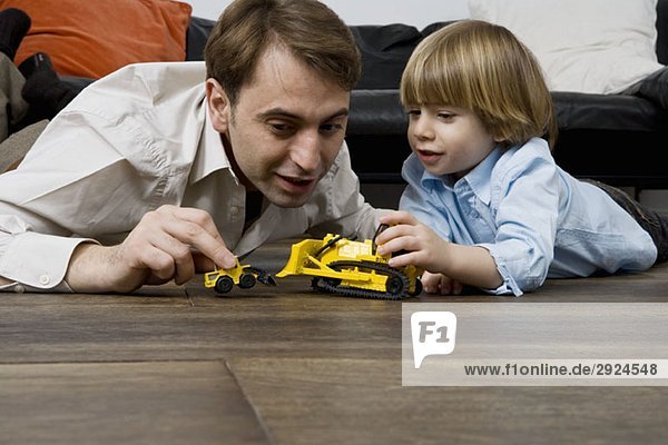 A father and son playing with toy trucks
