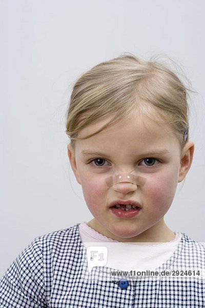 A young girl with a adhesive bandage on her nose