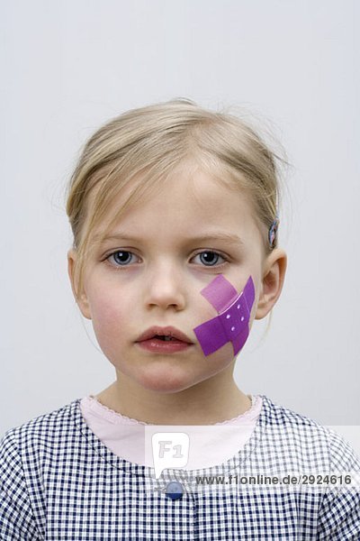 A young girl with a adhesive bandage on her cheek