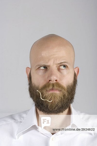 Ein Mann mit einer Nudel im Bart.