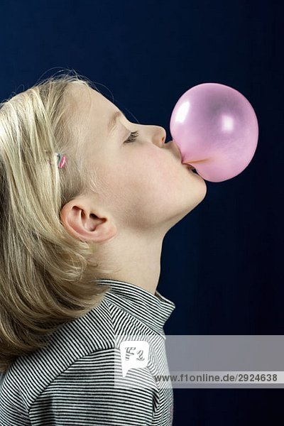 A young girl blowing a chewing gum bubble