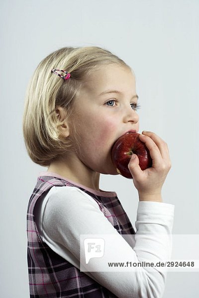 A young girl eating an apple