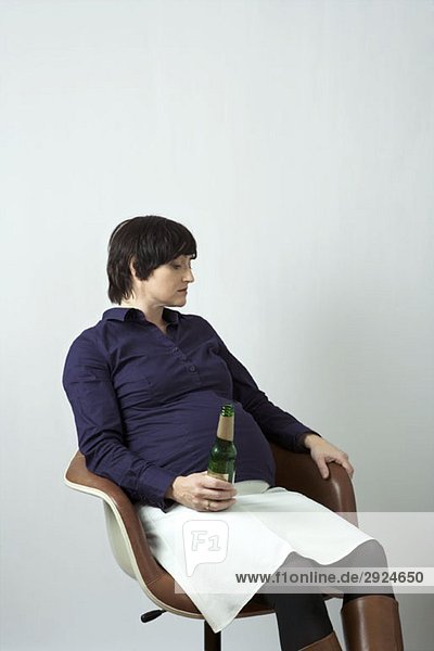 A pregnant woman holding a beer bottle