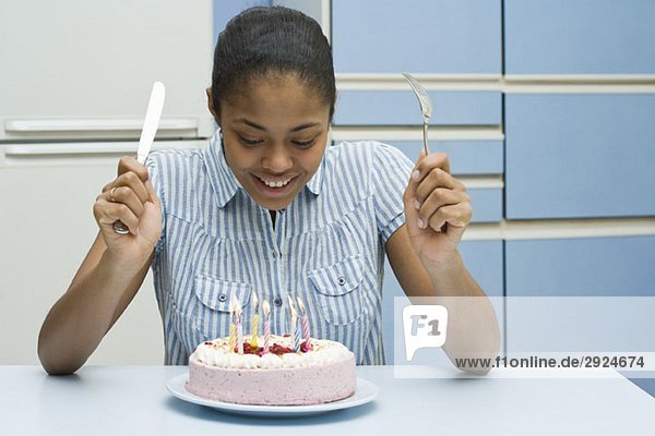 Eine junge Frau  die einen Geburtstagskuchen essen will.