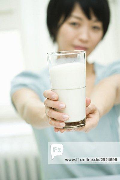 Eine Frau hält ein Glas Milch aus.