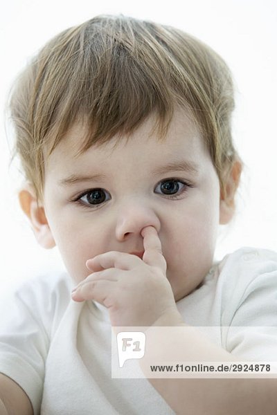 Ein kleiner Junge mit einem Finger in der Nase.