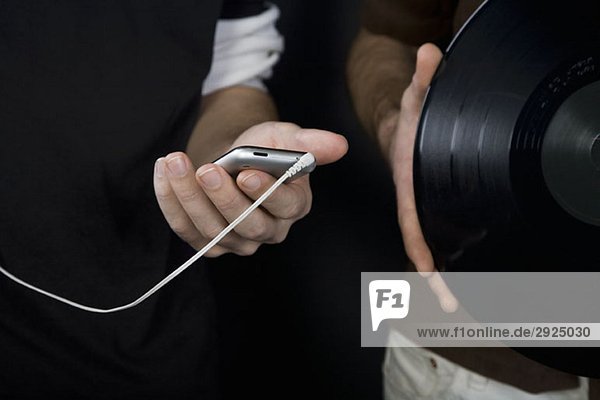 Ein Mann hält einen MP3-Player und ein anderer eine Schallplatte.