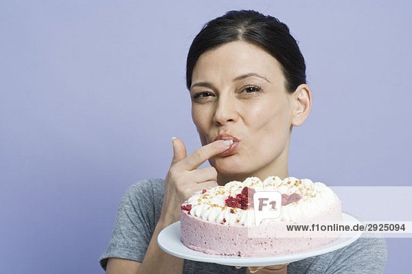 Eine Frau  die einen Kuchen mit dem Finger probiert.
