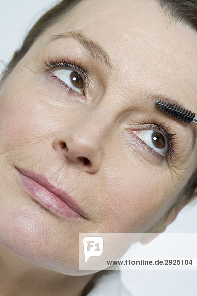 Eine Frau  die eine Schminkpinsel auf ihren Augenbrauen benutzt.