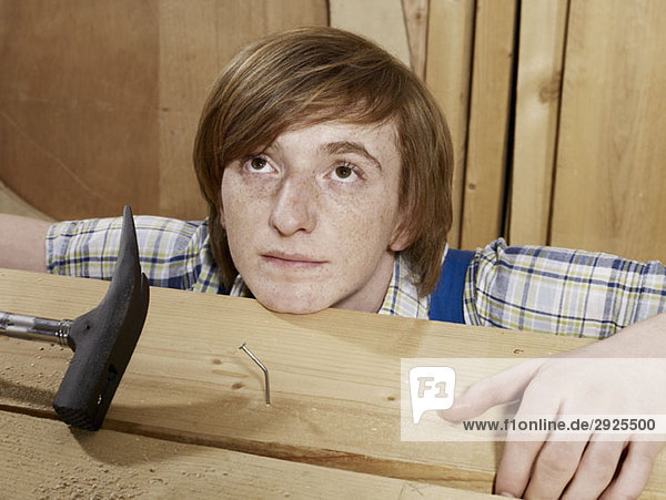 Ein junger Mann hinter einem gebogenen Nagel aus Holz.