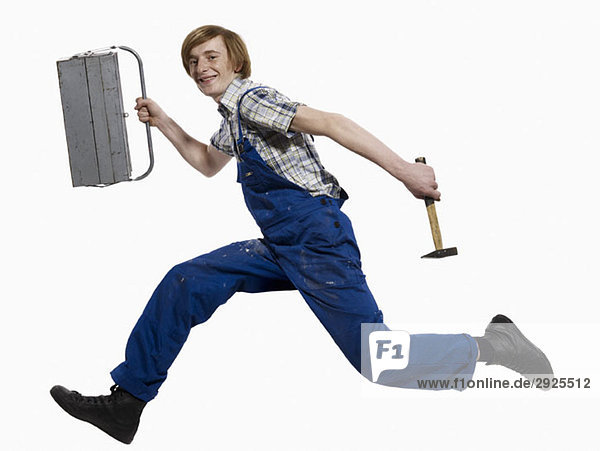 Ein junger Mann  der mit Werkzeugkasten und Hammer läuft.