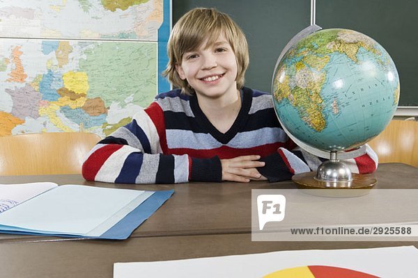 Porträt eines Schülers  der in der Nähe einer Kugel sitzt.