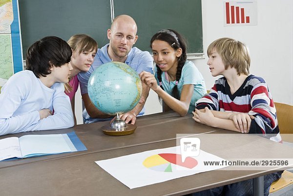 Schüler und ein Lehrer auf der Suche nach einem Globus