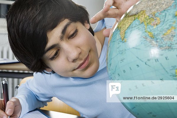 Ein Schuljunge schaut auf einen Globus