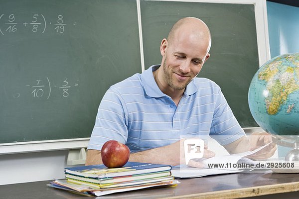 Ein Lehrer  der am Schreibtisch sitzt.