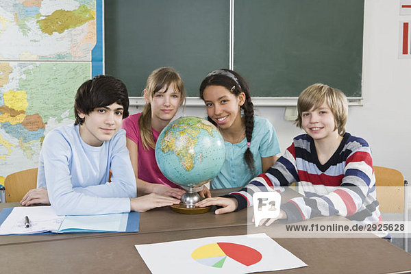 Schüler sitzen an einem Tisch mit Weltkugel